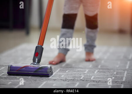 child using a vacuum cleaner while cleaning the carpet in the house Stock Photo