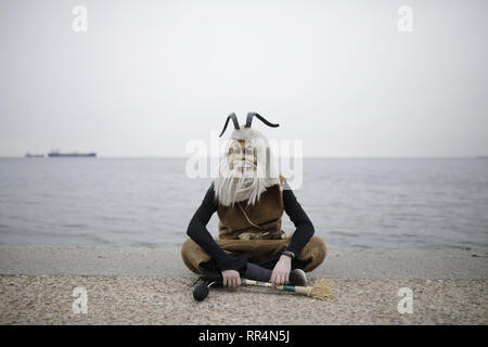 Thessaloniki, Greece. 24th Feb, 2019. A participant wearing a traditional costume sits at the seafront of Thessaloniki. The Folklife and Ethnological Museum of Macedonia organized the fifth European assembly of bell bearers in Thessaloniki. The assembly took place in the context of the action ''Bell Roads'', which attempts to explore the customs of bell bearing in Europe. Credit: ZUMA Press, Inc./Alamy Live News Stock Photo