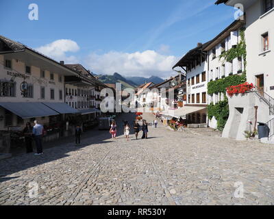 GRUYERES, SWITZERLAND on AUGUST 2018: View to old houses at street on main market square in swiss european town at canton of Fribourg with clear blue  Stock Photo