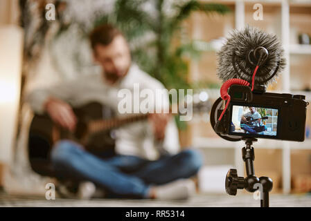 Blog about music. Close up of digital camera screen with male music blogger playing the guitar and recording new video lesson for his subscribers. You Stock Photo