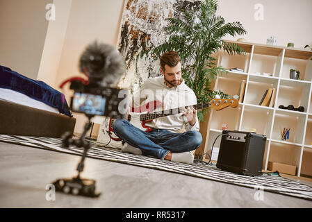 Power of music. Close up of digital camera screen with male music blogger playing electric guitar and recording new video for his vlog Stock Photo