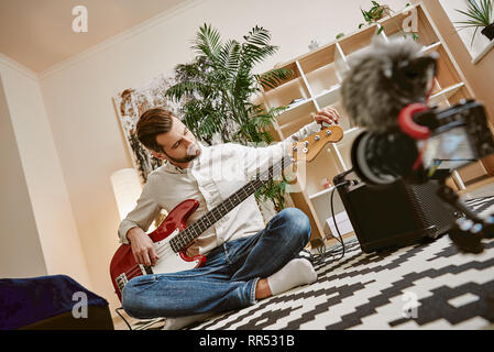 Preparing instrument. Handsome male music blogger adjusting electric guitar for recording new video lesson . Youtube channel. Music blog Stock Photo
