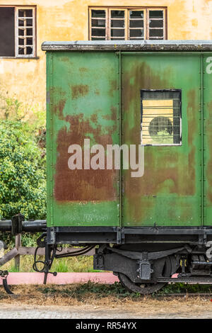 View of a abandoned and older rustic train wagon, yellow building as background, in Portugal Stock Photo
