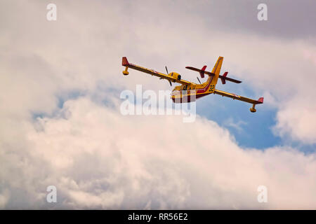LE BOURGET, FRANCE - JUNE 24, 2017. Small yellow red seaplane hydroplane flying in the sky with clouds at International aeronautical and spatial meeti Stock Photo