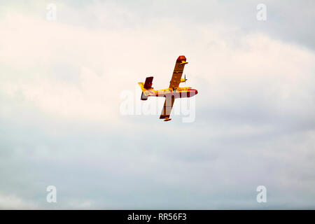 LE BOURGET, FRANCE - JUNE 24, 2017. Small yellow red seaplane hydroplane flying in the sky with clouds at International aeronautical and spatial meeti Stock Photo