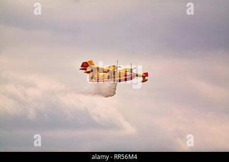 LE BOURGET, FRANCE - JUNE 24, 2017. Small yellow red seaplane hydroplane flying in the sky with clouds droping water at International aeronautical and Stock Photo