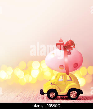 Easter egg and toy car on light bokeh background, happy easter day concept. Stock Photo