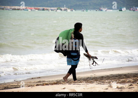 Thai man athletes walking on sand beach and carry kiteboard go to ocean for practicing sports and playing or sea kite at Ban Pae beach on July 3, 2018 Stock Photo
