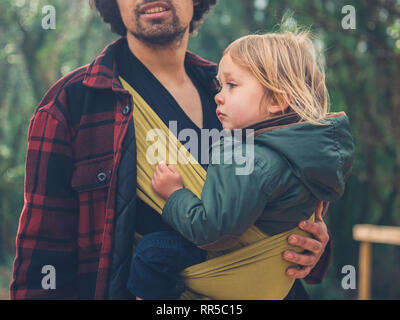A young father with a toddler in a sling is exploring the forest Stock Photo