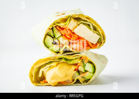 Vegan tofu wraps with cashew cheese sauce and vegetables, white background. Plant based food concept. Stock Photo