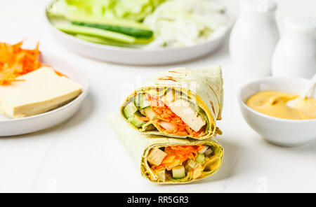 Vegan tofu wraps with cashew cheese sauce and vegetables, white background. Stock Photo