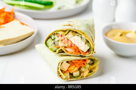 Vegan tofu wraps with cashew cheese sauce and vegetables, white background. Stock Photo