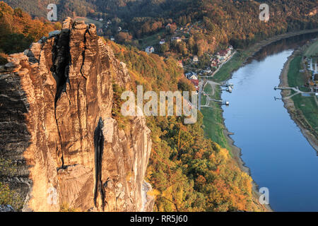 Rock formation and trees with evening sun in autumn. In the background forests and houses, in the valley of the river Elbe from the Saxon Switzerland Stock Photo