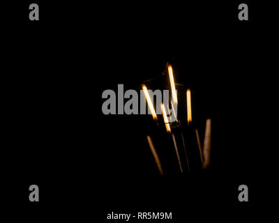 lightbulb on dark background with bright yellow shining wire Stock Photo