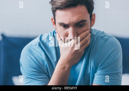 selective focus of stressed man covering mouth with hand at home Stock Photo