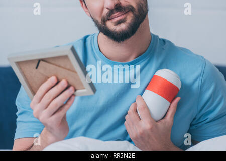 cropped view of man holding photo frame and funeral urn at home Stock Photo
