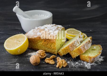 Mint cake on black surface with lemon, nuts, powdered sugar. Stock Photo