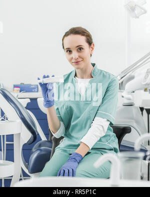 selective focus of cheerful female dentist holding toothpaste Stock Photo