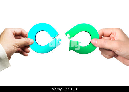 Circular economy concept. Male and female hands assembling arrow infinity recycling symbol of jigsaw puzzle pieces, isolated on white background. Stock Photo