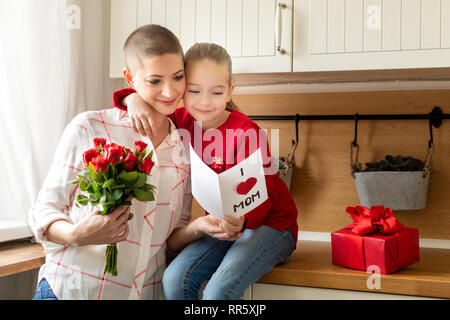 Adorable young girl and her mom, young cancer patient, reading a homemade greeting card. Family celebration concept. Happy Mother's Day or Birthday Ba Stock Photo