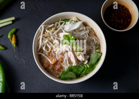 Asian rice noodles soup with vegetables and chicken in bowl. Top view flat lay. Stock Photo