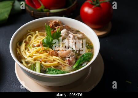 Asian soup noodles and chicken in bowl on dark background. Stock Photo