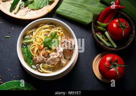 Asian soup noodles and chicken in bowl on dark background. Top view flat lay. Stock Photo