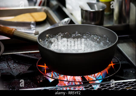 Chef cooking food, Preparation of soup in silver pan on gas, Kitchenware cooking Stock Photo