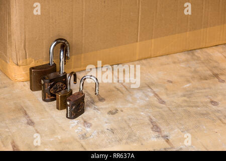 A line of old rusting unlocked padlocks arranged large to small. Stock Photo