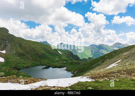 summer time in romanian carpathians. beautiful landscape of fagaras mountains. lake capra down in the valley. fluffy clouds above the ridge. view from Stock Photo