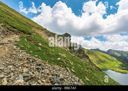 summer time in romanian carpathians. beautiful landscape of fagaras mountains. lake capra down in the valley. fluffy clouds above the ridge. rocky cli Stock Photo
