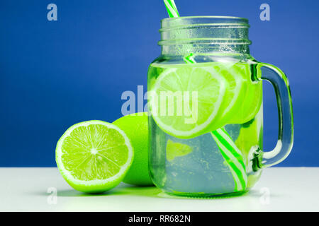 refreshing green citrus lemonade in jar. summer cocktail with ripe and juicy lemons and on a white table. vitamins Stock Photo