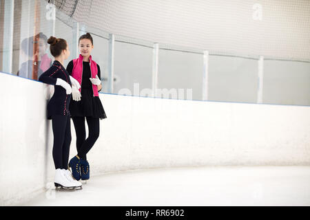 Full length portrait of two young girls chatting on rink during figure skating practice, copy space Stock Photo