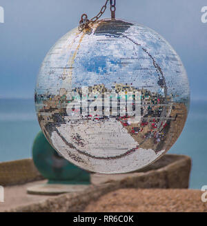 Mirrored gitter disco ball with a blue background. Abstract colours and shapes refelected in the silver ball. Stock Photo