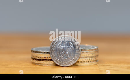 A Reichsmark coin from 1936 in front of a stack of old coins. Stock Photo