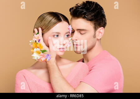 handsome boyfriend touching face of girlfriend with flowers on face  isolated on beige Stock Photo - Alamy