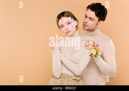 tender boyfriend with alstroemeria flowers on hand touching face of attractive  girlfriend isolated on beige Stock Photo - Alamy