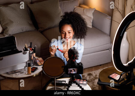 Young influencer making review for lipstick in living room Stock Photo