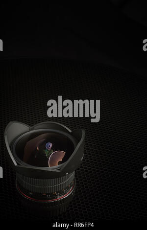 8mm fisheye camera lens with hood against a black background. Stock Photo