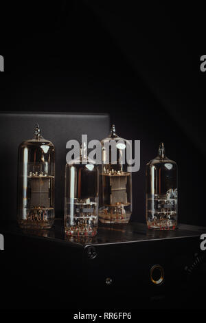 Headphone amplifier with four vacuum tubes / valves against a black background. Vertical / portrait aspect. Stock Photo