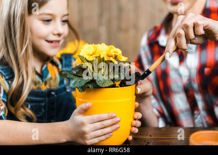 selective focus of kid holding pot near mother putting ground with shovel Stock Photo