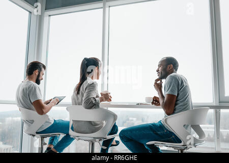 Happy joyful diverse business people laughing at funny joke talking at work break, cheerful corporate team office workers multi-ethnic young coworkers Stock Photo