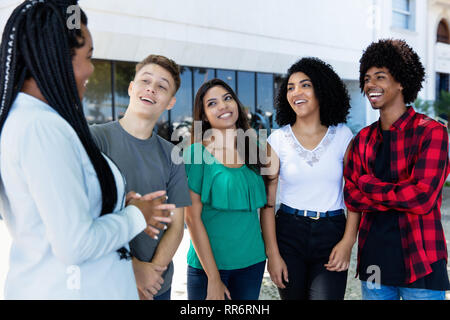 Latin american young adult people talkin with african woman outdoor in the city Stock Photo