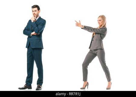 businesswoman pointing with hand gun at male colleague, isolated on white Stock Photo