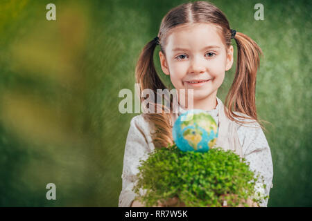 selective focus of smiling child with flower pot and globe model on blurred background, earth day concept Stock Photo