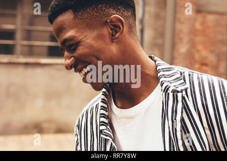Close up of smiling african man in casuals. Young guy looking happy outdoors. Stock Photo