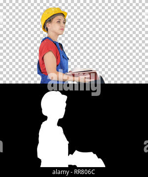 On Alpha Matte. Medium shot. Side view. Woman construction worker in hard hat and workwear uniform checking the list, Alpha Channel Professional shot  Stock Photo
