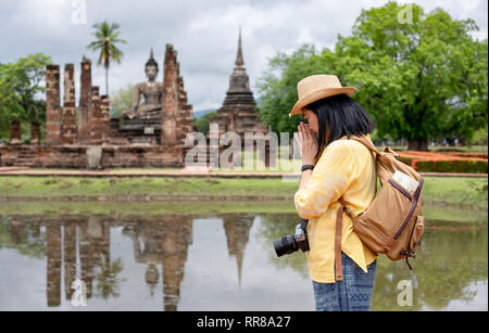 Asian tourist woman pay respect to buddha at ancient of pagoda temple thai architecture at Sukhothai,Thailand. Female traveler in casual thai cloths s Stock Photo