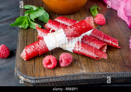 ripe fresh juicy raspberries and fruit leather rolls on dark background. Detox concept. Healthy food, Fruits amazing candy. copy space, Stock Photo