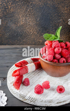 ripe fresh juicy raspberries and fruit leather rolls on dark background. Detox concept. Healthy food, Fruits amazing candy. copy space, Stock Photo